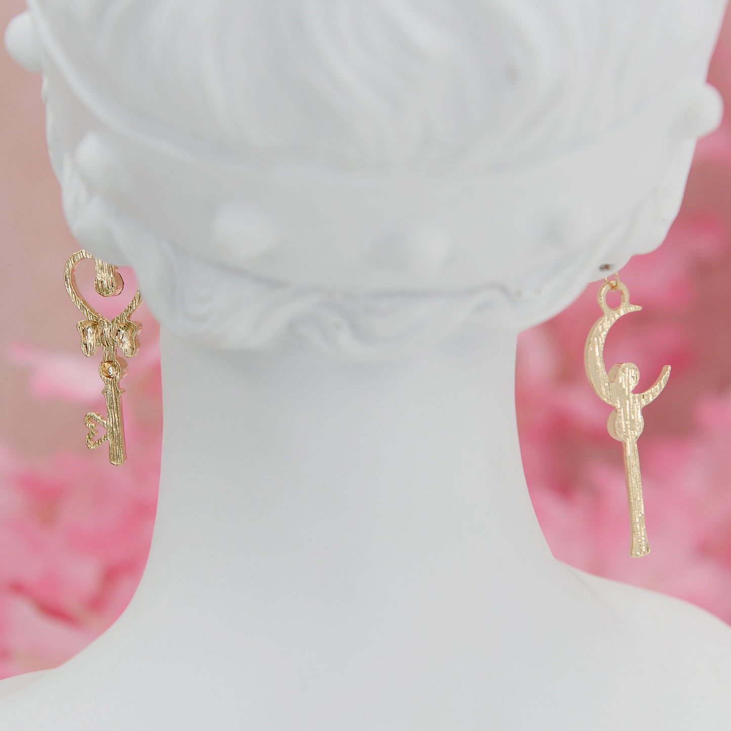 Asymmetrical earrings, inspired by the warriors' scepter from Sailor Moon. One earring features a sleek, scepter design with delicate details, the other showcases a crescent moon charm for a celestial touch.